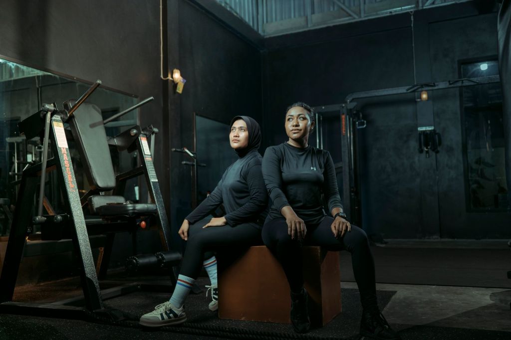 Two women in gym gear sitting in a modern gym