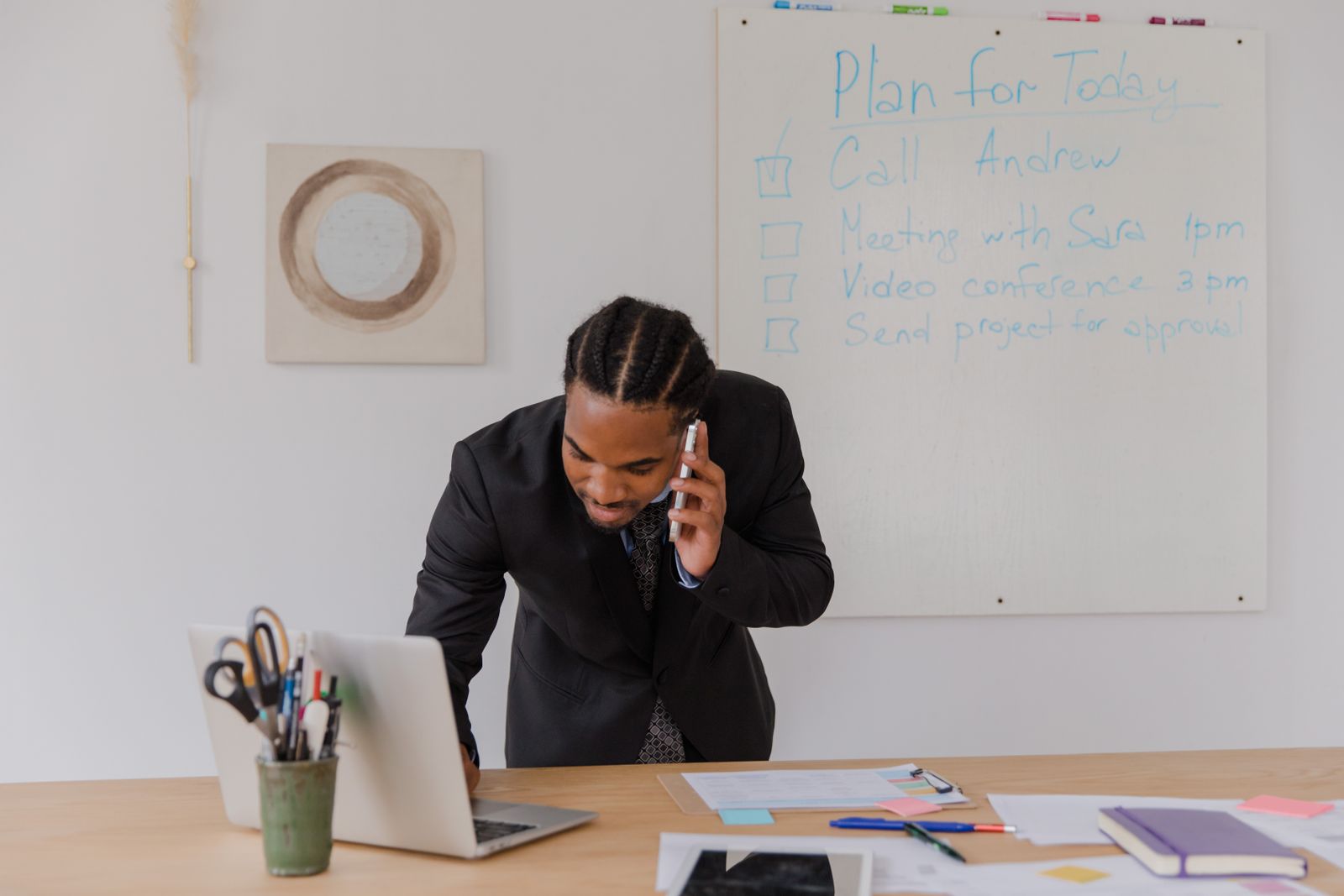 A business owner on the phone at his desk with a laptop open