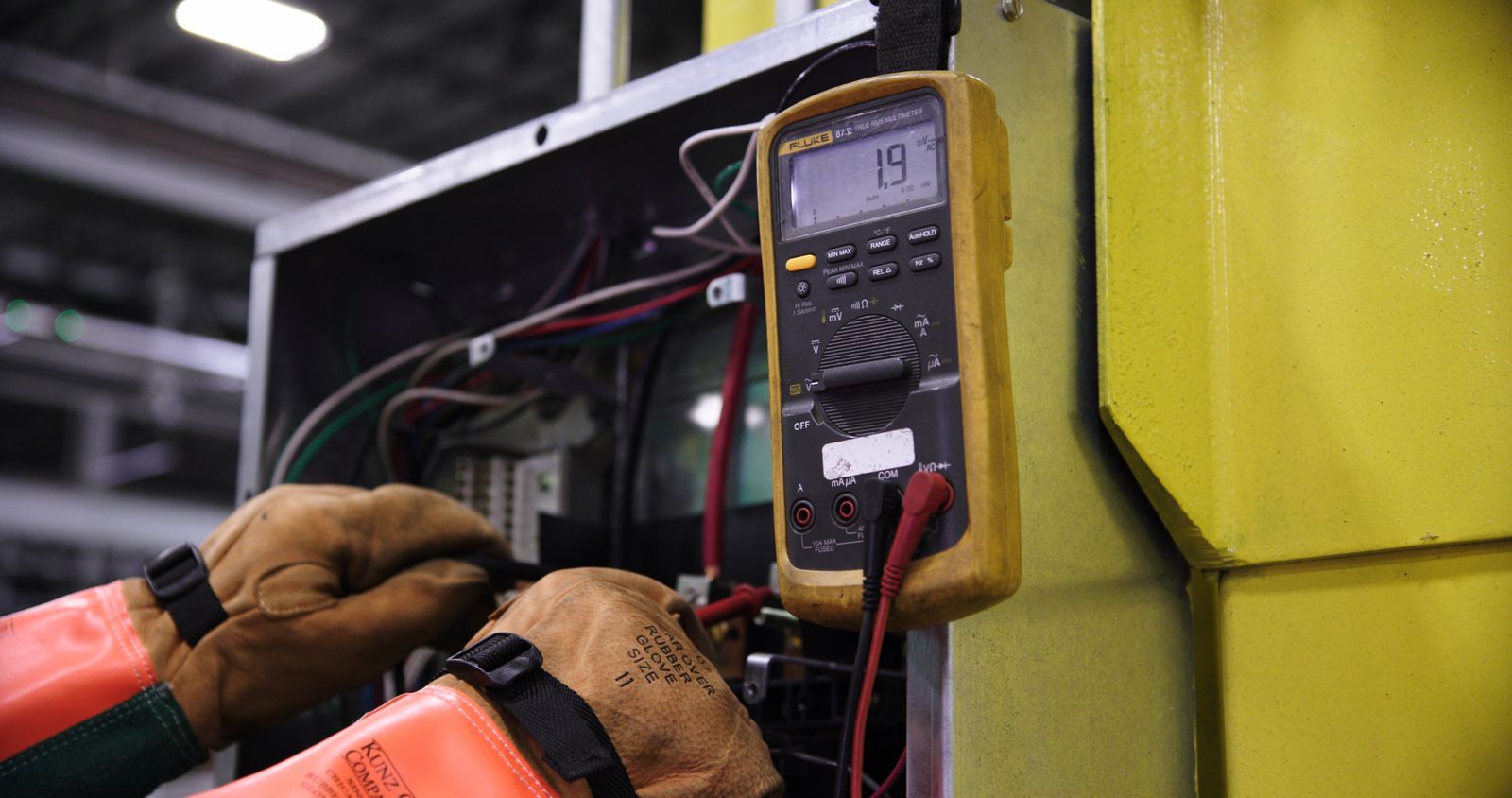 Electrician using a multimeter on electrical panel wiring