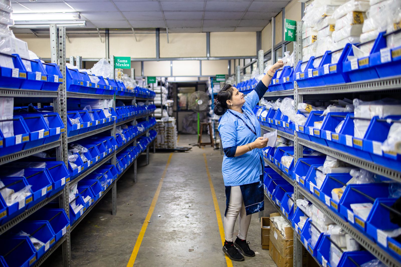 Worker organizing inventory bins on warehouse shelves