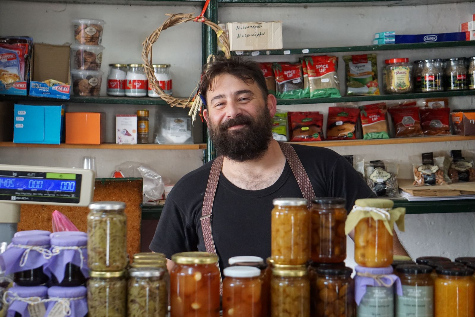 Smiling shopkeeper standing behind a counter of jarred goods