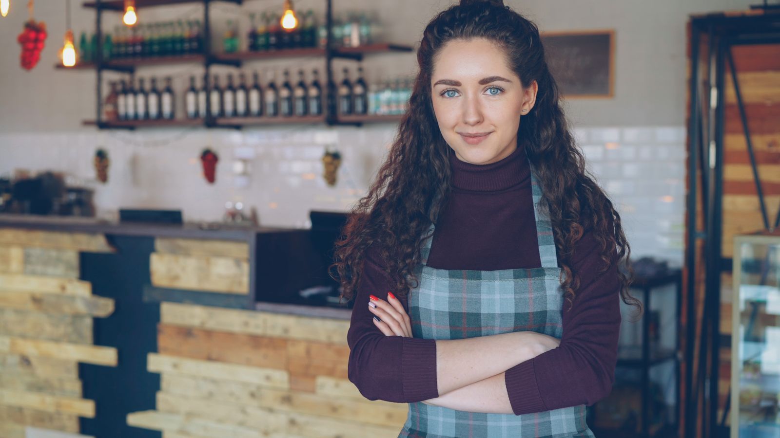Cafe owner standing with arms crossed in her coffee shop