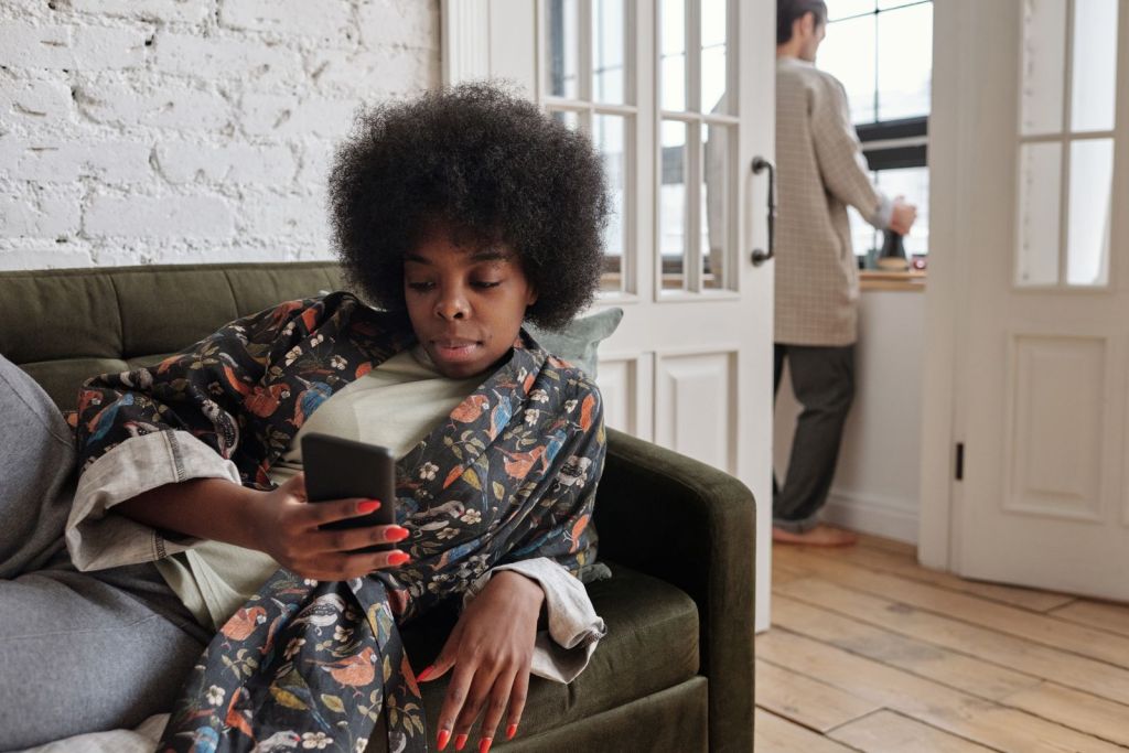 Woman relaxing on a sofa while texting on her phone