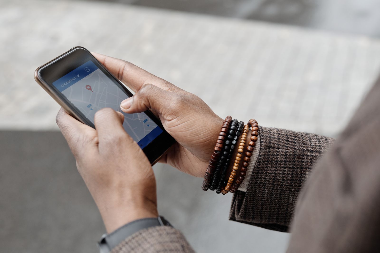 Hands holding a smartphone with a map app open outdoors