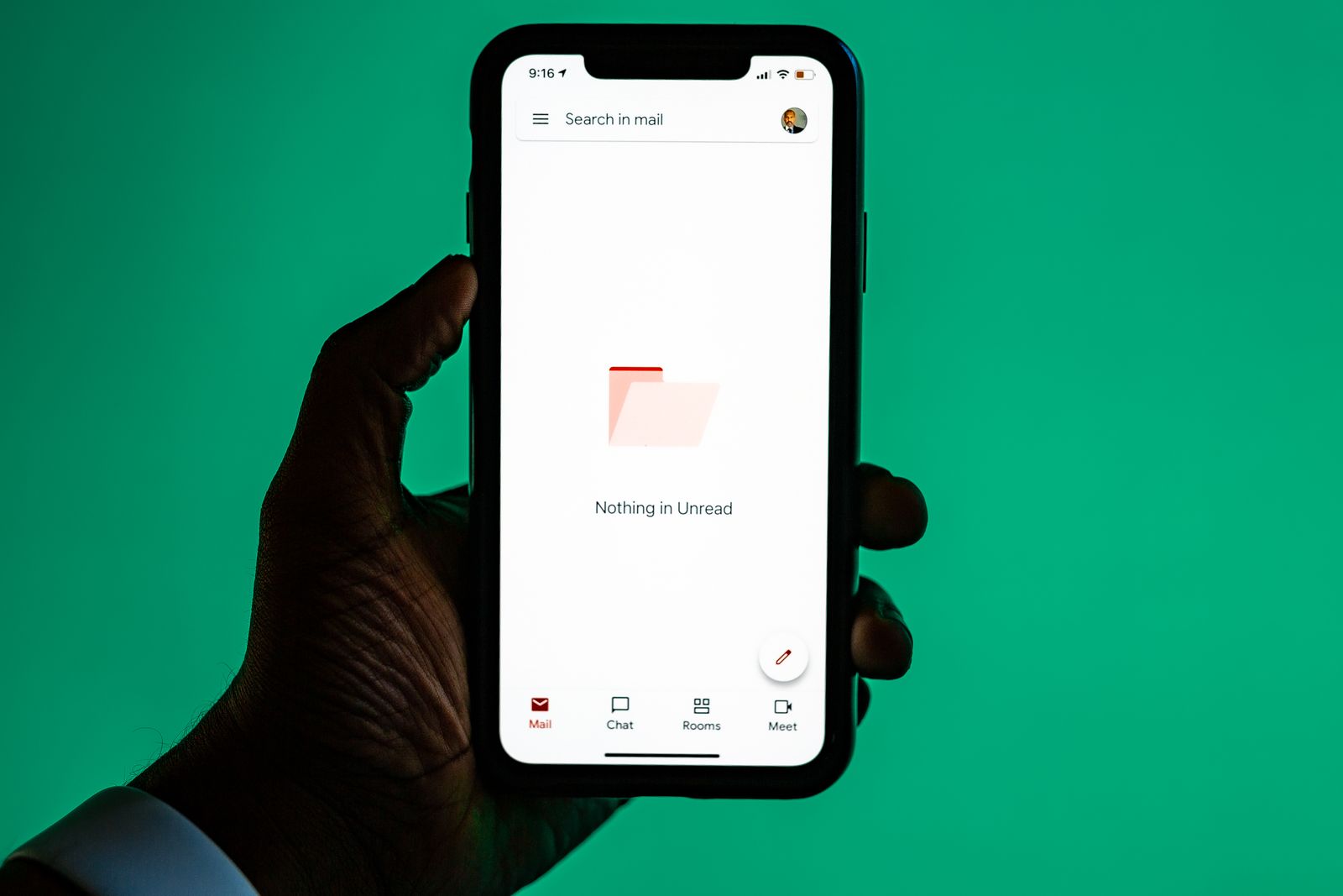 Hand holding a smartphone with an email app open