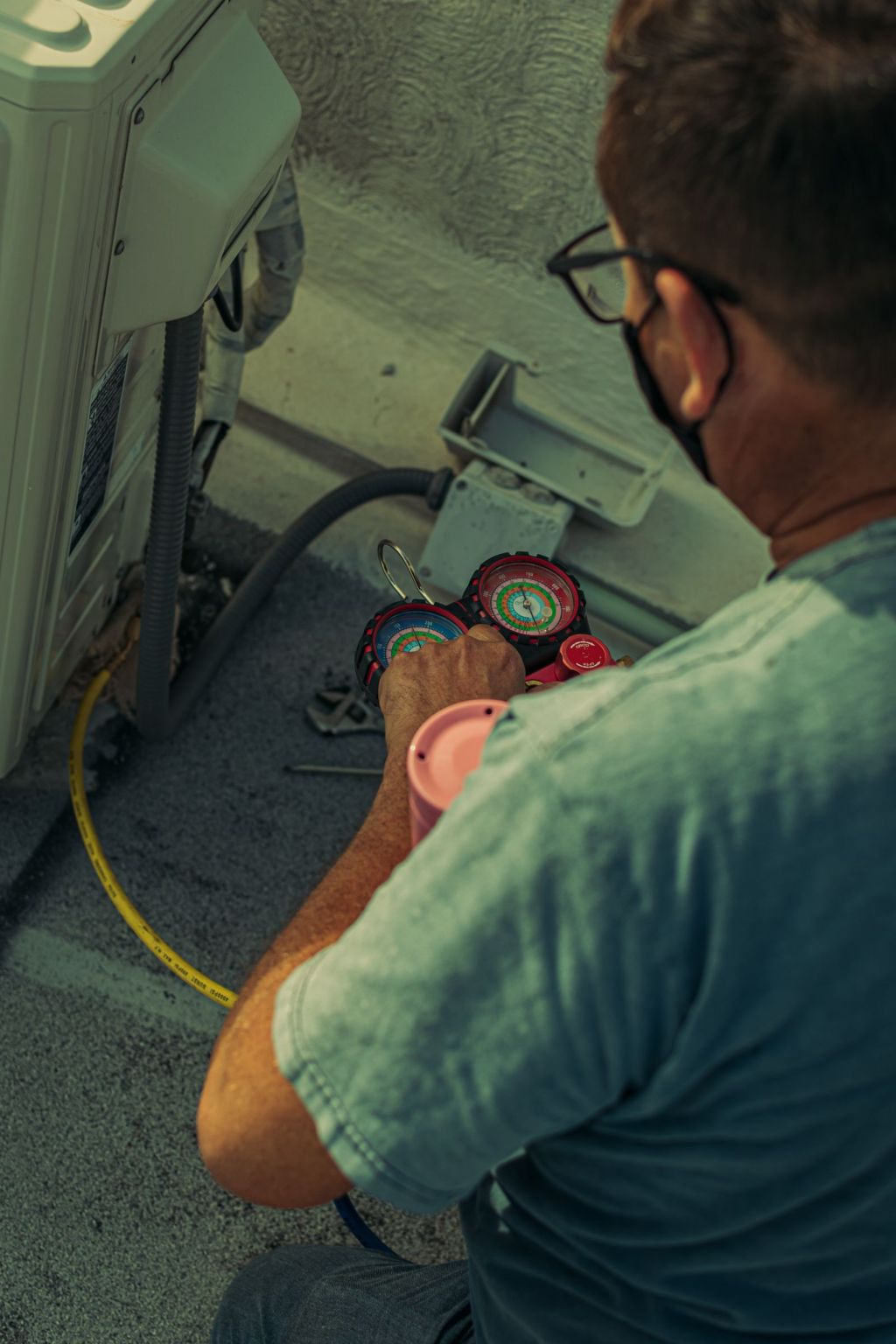 HVAC technician checking an air conditioning unit with a refrigerant gauge