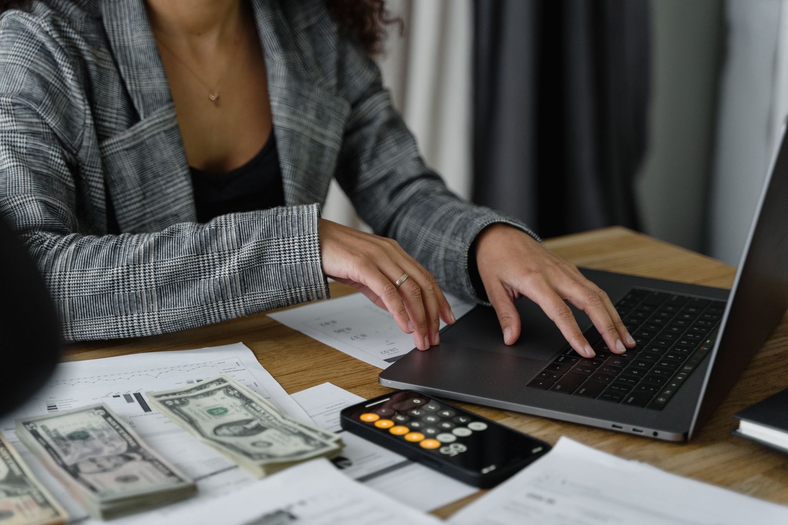 Businesswoman working on a laptop with cash and a calculator on the desk