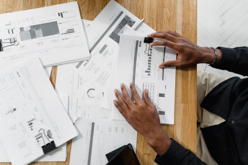 Top-down view of someone sorting financial documents on a wooden table