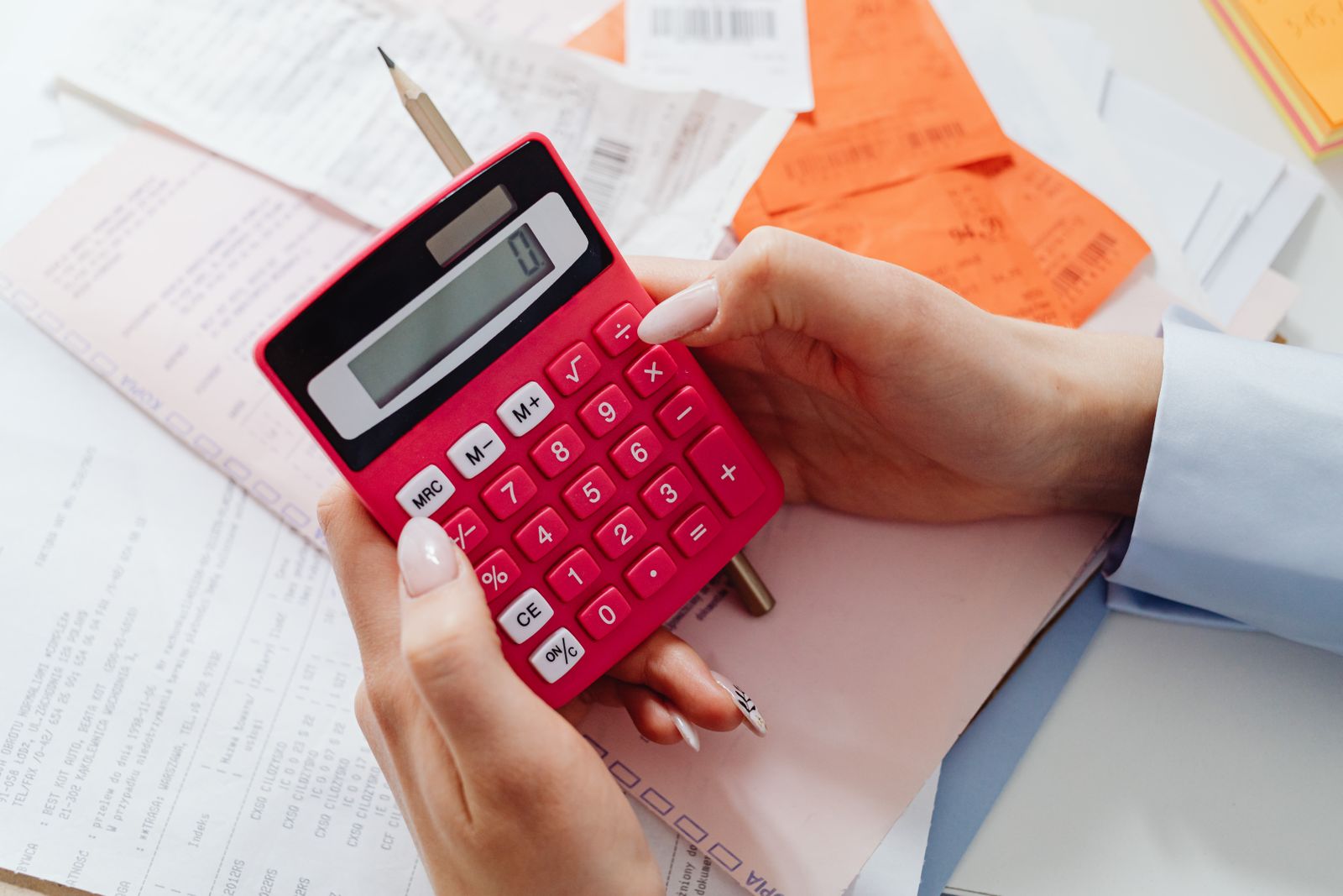 Hands holding a calculator over invoices and receipts