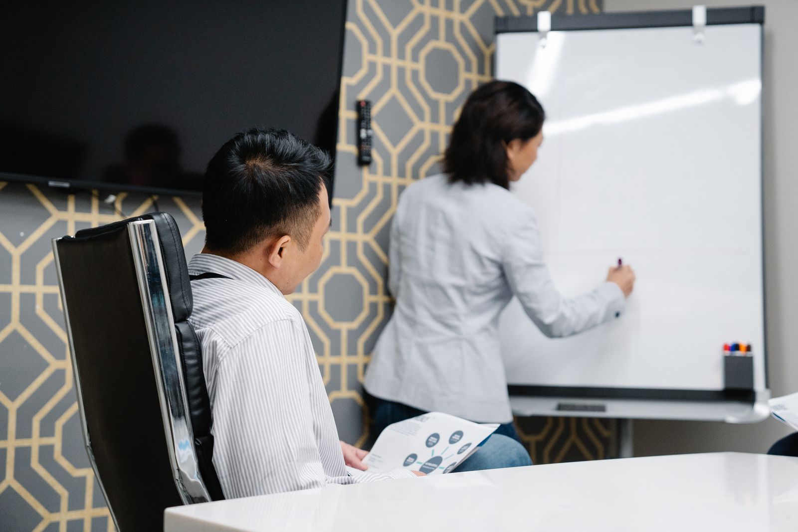 Woman writing on a whiteboard while a colleague watches