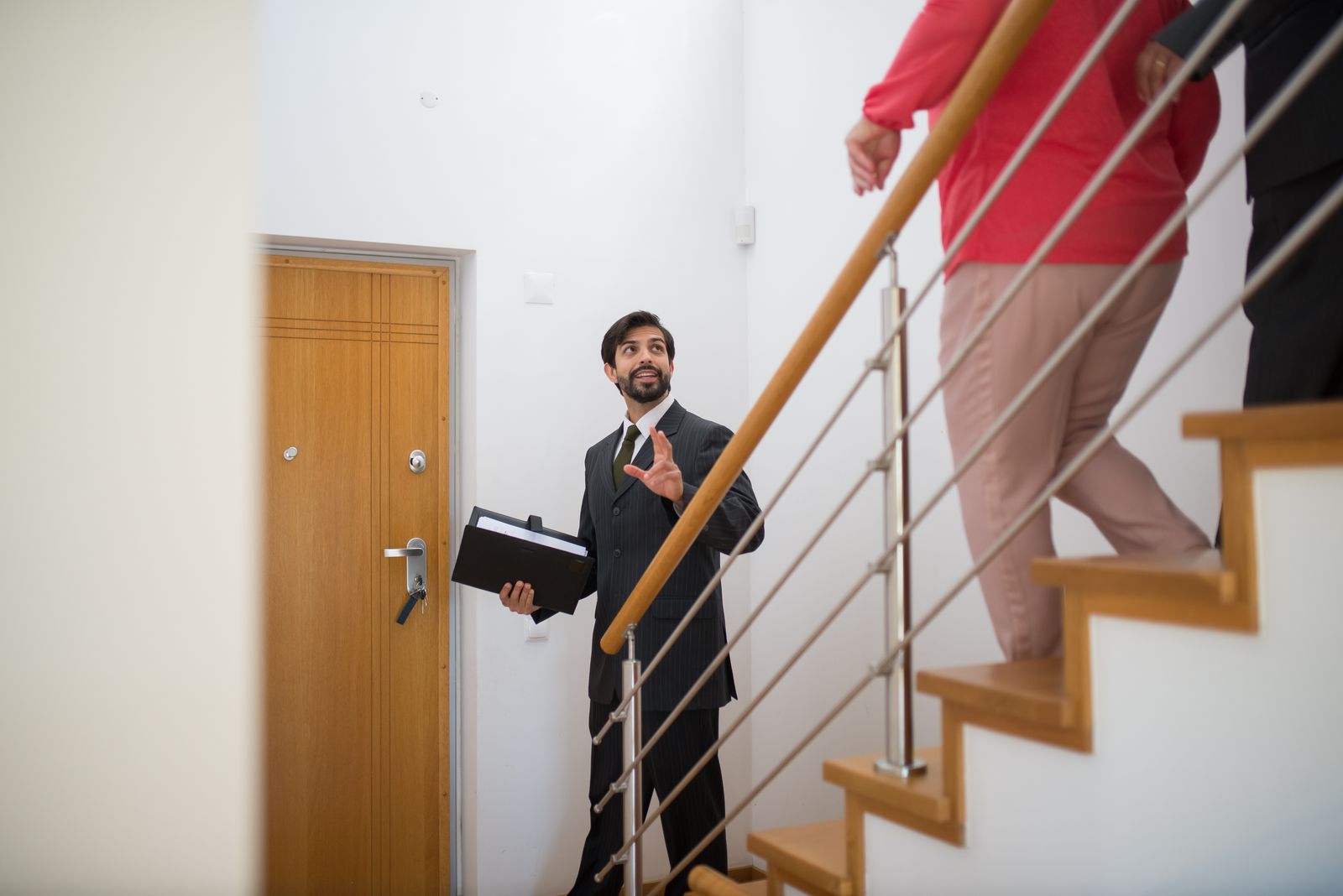 Real estate agent leading buyers up the stairs of a home