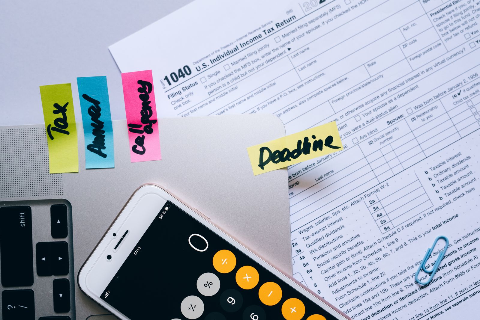 Flat lay of tax forms, sticky notes and a phone calculator