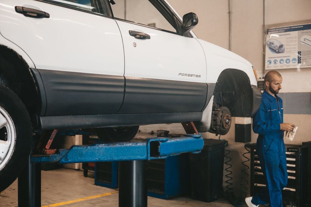 Mechanic inspecting a car raised on a lift in an auto repair shop