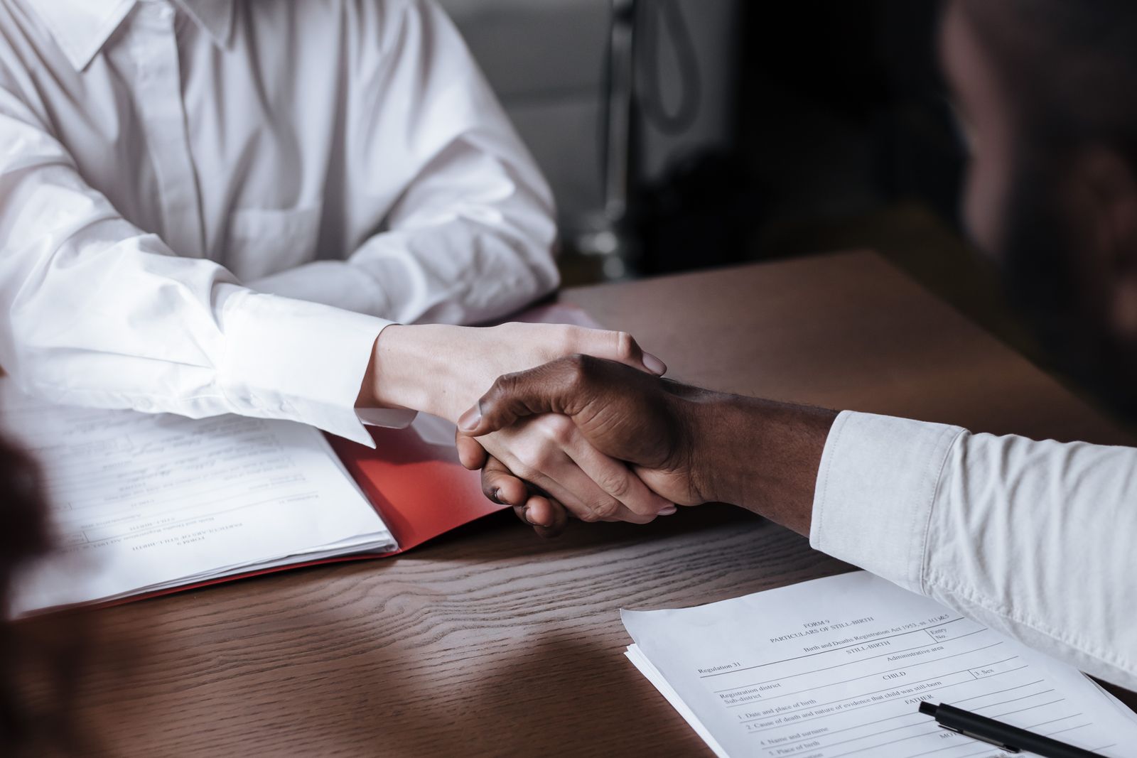 Close-up of a business handshake over documents on a desk