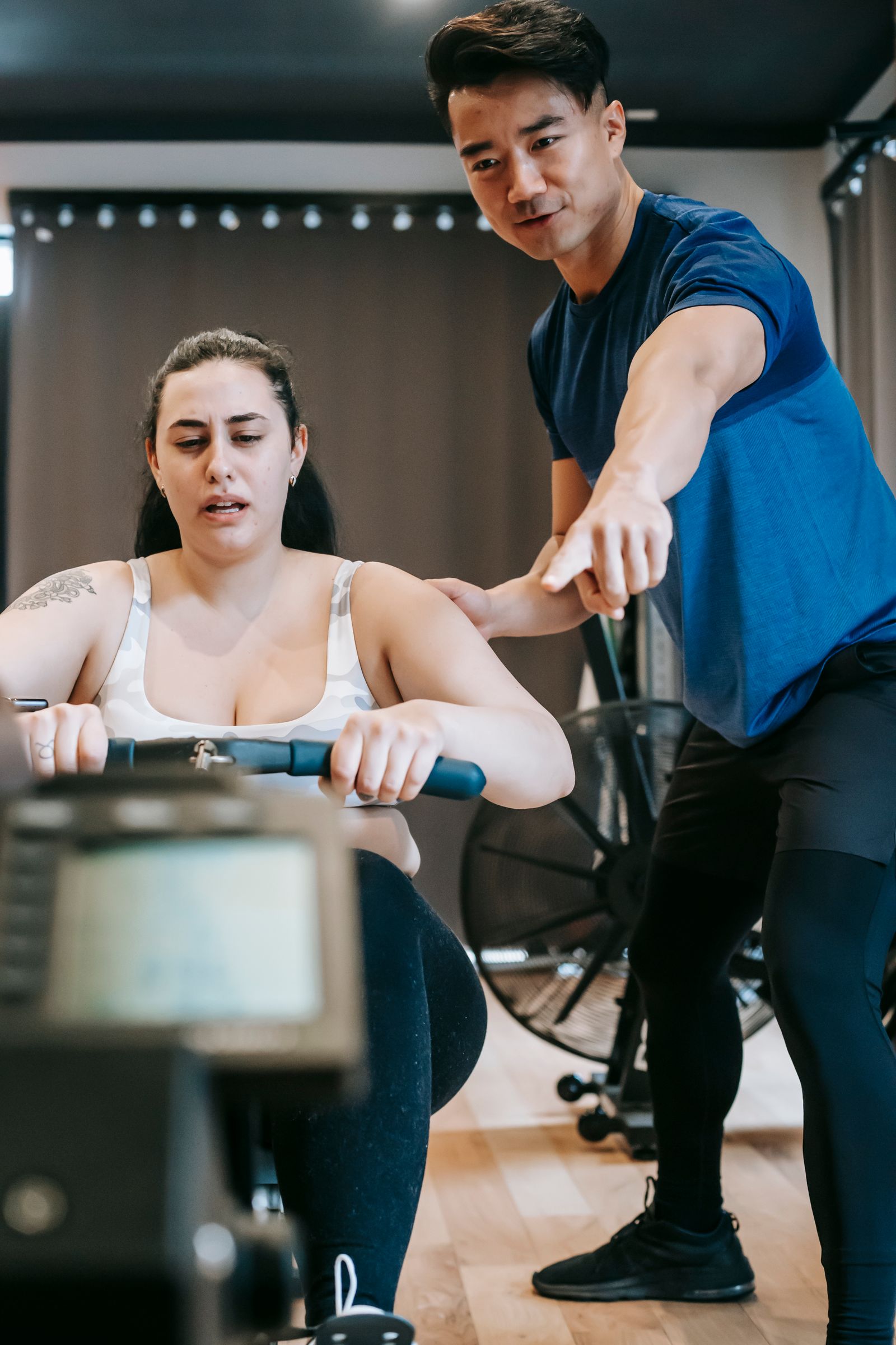 A personal trainer helping a woman on a rowing machine at the gym